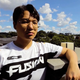Kim wears a Fusion jersey on top of a building with clouds and trees in the background.